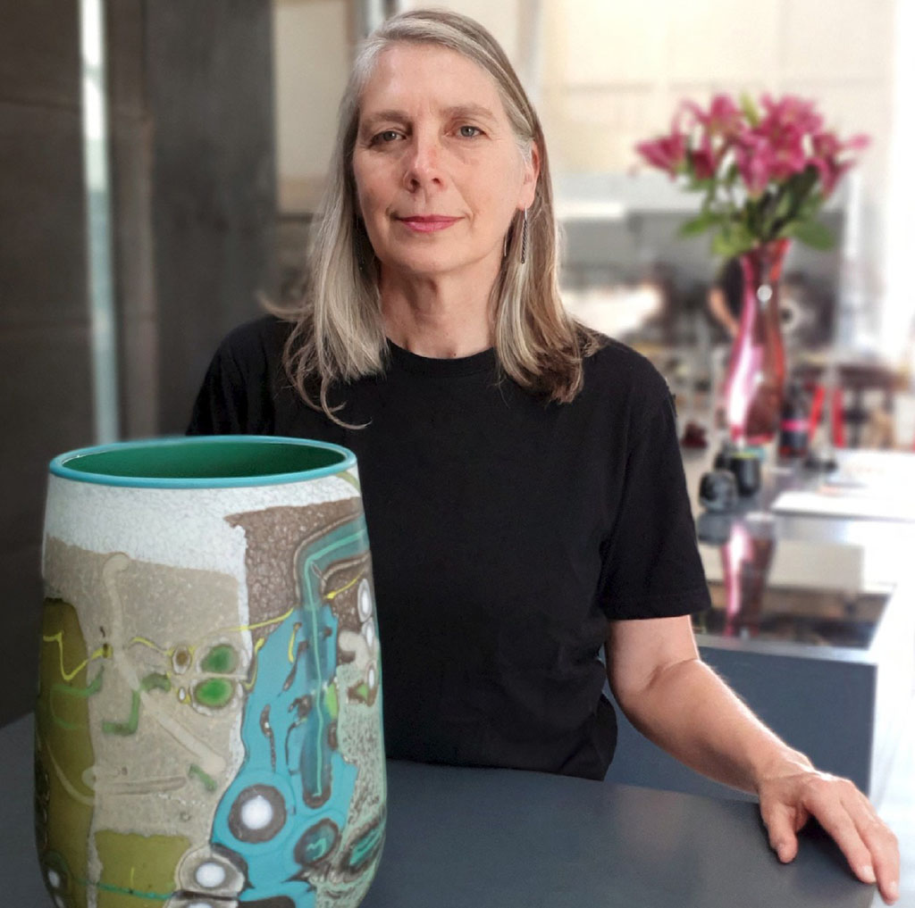 Woman holding large abstract ceramic vase indoors
