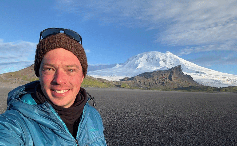 Person smiling before snow-covered mountain landscape