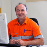 Man in orange safety shirt at computer