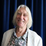 Smiling person in floral shirt and white jacket