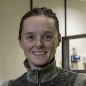 Smiling woman in green zip-up jacket indoors