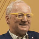 Smiling older man wearing yellow glasses and suit