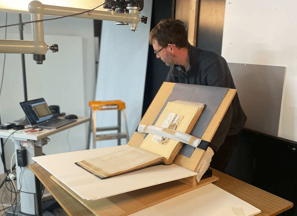 Archivist digitizing large antique book on cradle